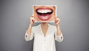 A woman holding a picture of a smiling mouth.