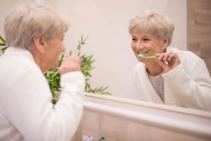 A woman is brushing her teeth in front of a mirror.